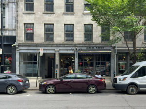 The Camtec store front. Above, rows of windows from the upper floor. In front a dark car blocking the view.