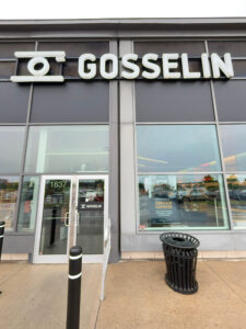 Store front of Gosselin. There is a bollard, a garbage can and the Gosselin sign. The front is a full glass facade.