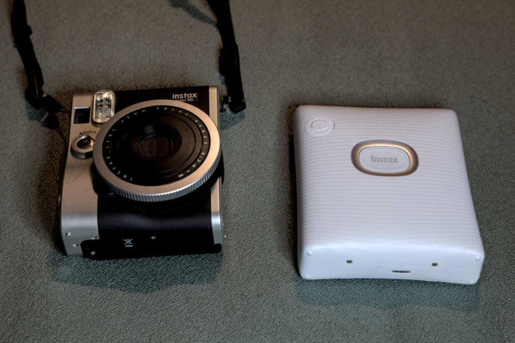 The Instax Square Link compared for size to an Instax Mini 90. Both are roughly the same size.